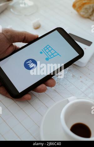 closeup of a man in a restaurant paying the bill with his smartphone through a wireless payment terminal placed on the table, set with a white tablecl Stock Photo
