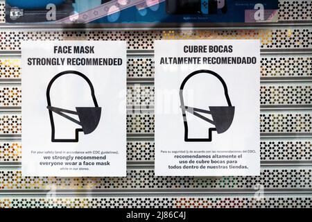 Bilingual mask signs outside a store in Astoria, Queens, New York encouraging masks even thought they're not mandated. Stock Photo