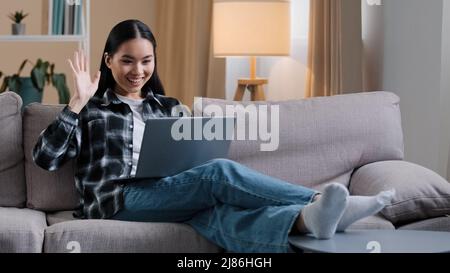 Asian girl woman business woman freelancer korean female with laptop video call chat conference calling talking on webcam waving hello distant Stock Photo