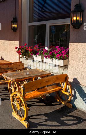 Biel, Switzerland - Mai 11, 2022: Wooden outdoor inn benches in the shape of a peasant wagon. Stock Photo