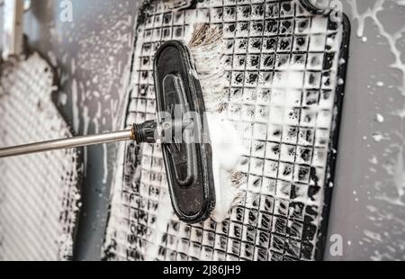 Car rubber mats being washed in carwash - detail on brush and white soap foam Stock Photo