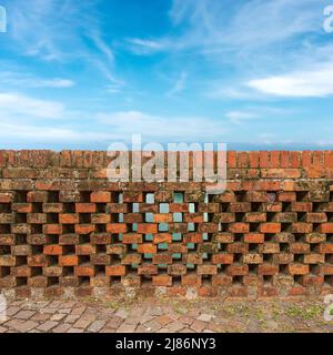 Close-up of a railing of a bridge (parapet) made of old bricks against a blurred blue sky with clouds. Veneto, Italy, Europe. Stock Photo