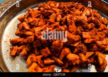 Tasty Indian Mango pickle preparation at home. Homemade Mango pickle or Aam ka achar preparation with sliced raw mangoes and red chilly powder with sp Stock Photo