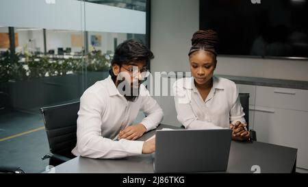 Multiethnic business team diverse people brainstorm in office two arabian men and african woman using laptop computer discussing startup coworkers Stock Photo