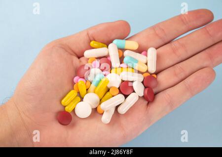 Man holding variety of medicine pills, capsules and tablets in his hands. A handful of pills. Immune system vitamins and supplemets. Man's health conc Stock Photo