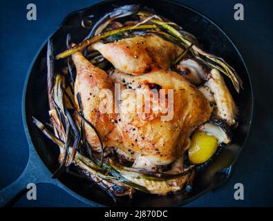 Roast chicken with vegetables and lemon in a cast iron skillet Stock Photo