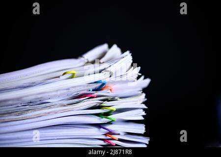 Multicolored paper clips on stack of paperwork  Stock Photo