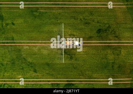 top down view of the tractor spraying the chemicals on the large green field, agriculture concept Stock Photo