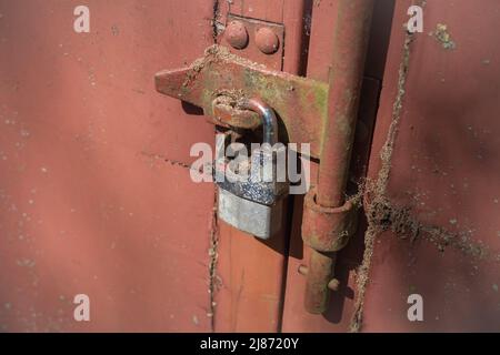 Close up of an old and rusty padlock securing the door of a metal container Stock Photo