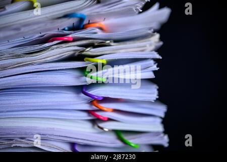 Multicolored paper clips on stack of paperwork  Stock Photo