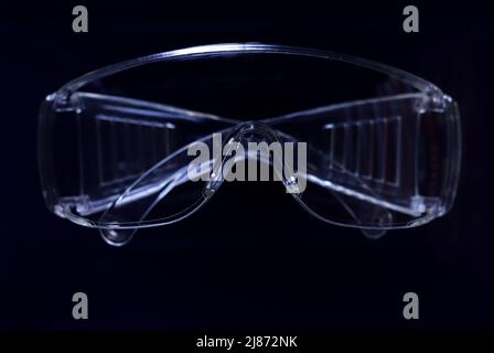 Protective glasses on dark background, healthcare and safety concept. Safety glasses on black background. Personal protective equipment. Goggles. Stock Photo