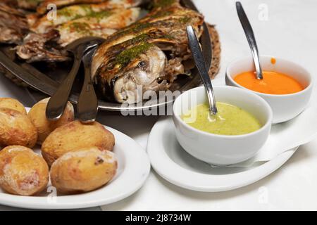 Wrinked potatoes (papas arrugadas) served with red sauce (mojo rojo) and green herby (mojo verde) plus a platter of grilled fish in Tenerife. The pota Stock Photo