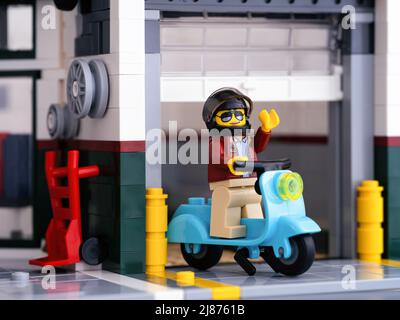 Tambov, Russian Federation - January 03, 2022 A Lego woman minifigure leaving a garage on her moped Stock Photo