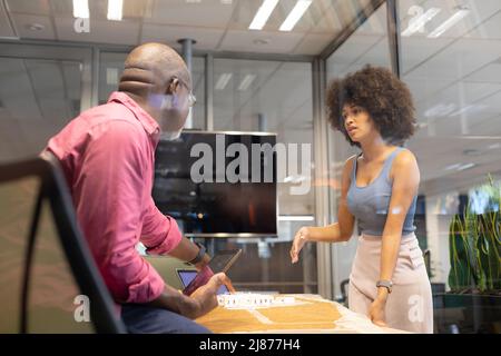 Multiracial male and female colleagues discussing while planning together in boardroom at workplace Stock Photo