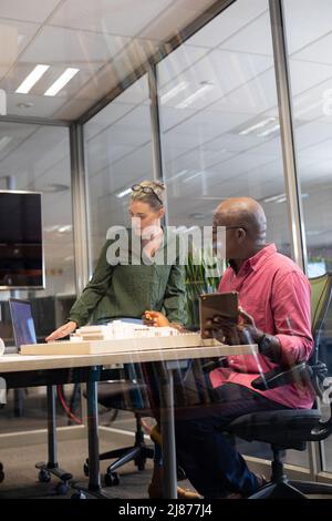 Confident multiracial architects discussing over model at desk in modern workplace Stock Photo