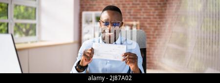 Close-up Of A Smiling Businessman Showing Company Cheque Stock Photo