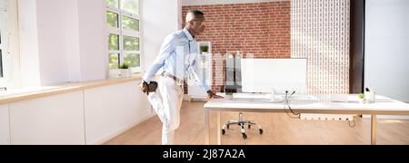 Young Businessman Looking At Folders On Shelf Doing Yoga Stock Photo