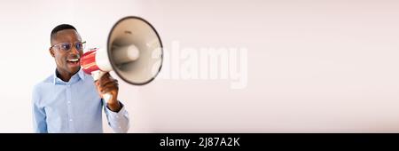 Close-up Of A Beard Man Shouting Through A Megaphone Against Gray Background Stock Photo