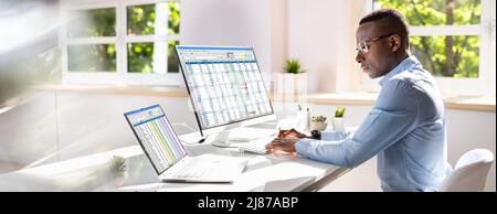Side View Of Businessman's Hand Analyzing Data On Computer Over Desk Stock Photo