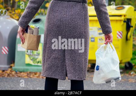 Aware woman separating paper from other waste, putting it into green container to save natural resources in Prague Chezh Stock Photo