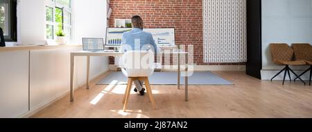 Rear View Of A Businessman Working On Desktop Computer In Office Stock Photo