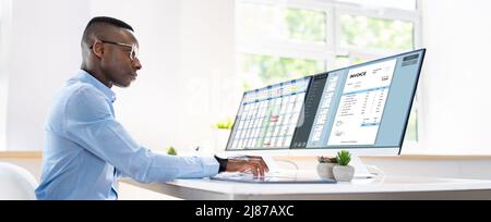 Businessperson Analyzing Invoice On Computer In Office Stock Photo