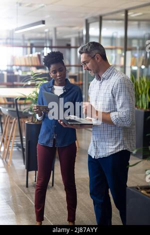 Multiracial colleagues discussing over laptop while planning together at modern workplace Stock Photo
