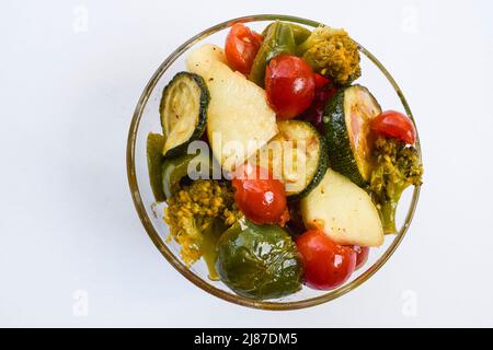 Tasty and Healthy bowl full of Salad with different vegetables lik sliced Zuccini, baby tomato whole, broccoli, with dip on blue background topviewon Stock Photo