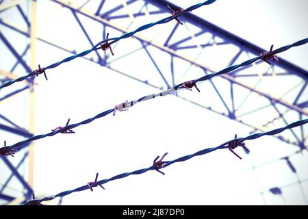 three barbed wires in a prison camp for the segregation of prisoners and avoid escape with an overexposed antiqued effect Stock Photo