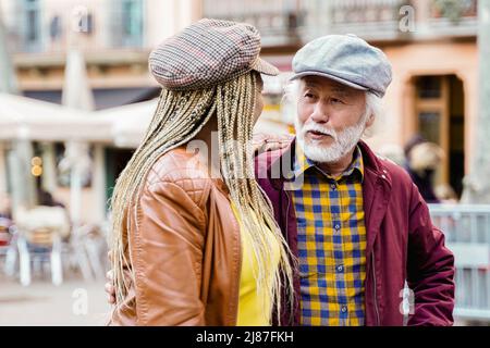 Multiethnic senior couple having fun walking by the city - Travel, elderly people concept - Focus on Asian man face Stock Photo