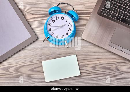 Alarm clock with blank paper for copy space on wooden desk. Top view flat lay. Stock Photo