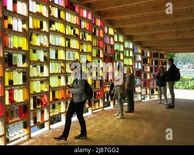 Visitors walk through the Almeerse Wolunie pavilion where a wall of glass jars of vegetable dyes represent the shades of nature; Floriade 2022 Stock Photo