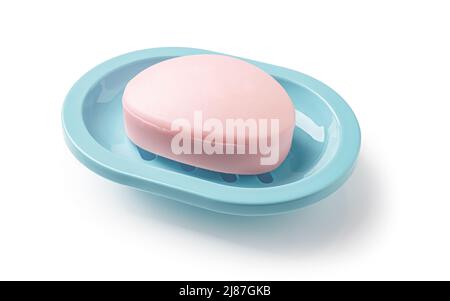 Pink soap bar in a teal blue dish isolated on a white background. Oval shaped soap bar on a plastic holder for bathroom and shower. Toiletries, purity Stock Photo