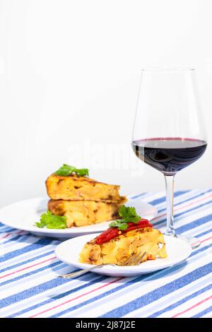 Traditional Spanish snack tortilla patatas served with red piquillo pepper and a glass of wine. Stock Photo