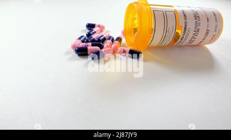 Amoxicillin capsules on a white background; antibiotic used to treat bacterial infections; doctor prescribed medication for infection treatment. Stock Photo