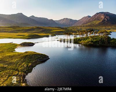 Aerial view of Twelve Pines Island, standing on a gorgeous background formed by the sharp peaks of a mountain range called Twelve Pins or Twelve Bens, Stock Photo