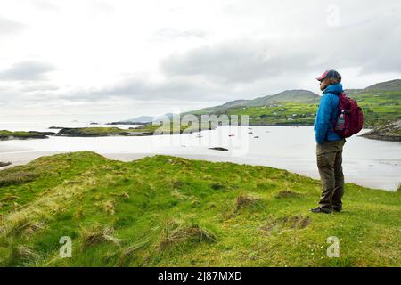 Male tourist admiring the Abbey Island, the idyllic patch of land in Derrynane Historic Park, famous for ruins of Derrynane Abbey and cementery, locat Stock Photo