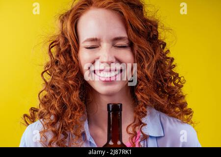 redhaired ginger woman holding non alcoholic alcohol wine bottle and feeling good emotions Stock Photo