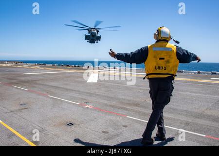 PACIFIC OCEAN (May 11, 2022) Aviation Boatswain’s Mate (Handling) Airman Corey Martin, a native of Jacksonville, Florida, signals to a CH-53D Sea Stallion, attached to Marine Heavy Helicopter Squadron (HMH) 462, aboard amphibious assault ship USS Essex (LHD 2), May 11, 2022. Essex is underway conducting routine operations in U.S. 3rd Fleet. (U.S. Navy photo by Mass Communication Specialist Seaman Donita Burks) Stock Photo