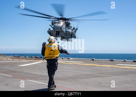 PACIFIC OCEAN (May 11, 2022) Aviation Boatswain’s Mate (Handling) Airman Corey Martin, a native of Jacksonville, Florida, signals to a CH-53D Sea Stallion, attached to Marine Heavy Helicopter Squadron (HMH) 462, aboard amphibious assault ship USS Essex (LHD 2), May 11, 2022. Essex is underway conducting routine operations in U.S. 3rd Fleet. (U.S. Navy photo by Mass Communication Specialist Seaman Donita Burks) Stock Photo