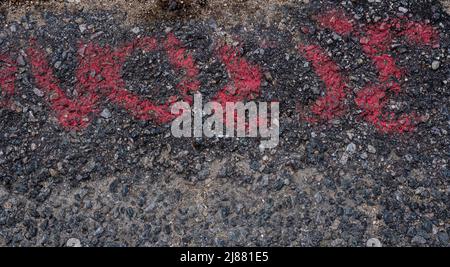Red painted markings on black and brown gravel pavement background texture Stock Photo