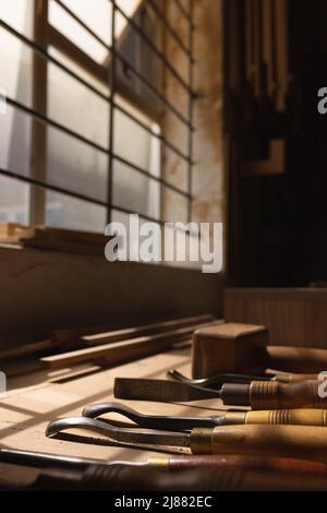 Close-up of various hand tools with wood shavings on workbench at workshop Stock Photo