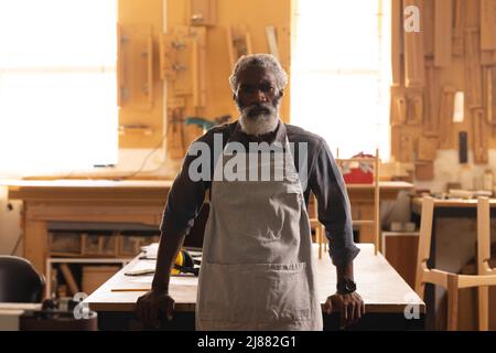 Portrait of confident african american mature carpenter standing in workshop Stock Photo