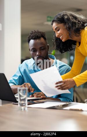 Young multiracial professionals planning while discussing together over file at modern workplace Stock Photo
