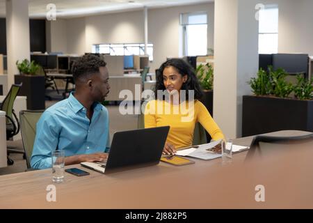 Confident male and female biracial business colleagues discussing while planning together at desk Stock Photo