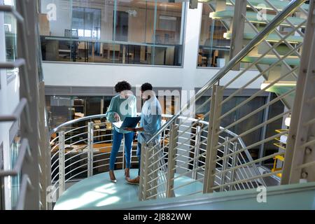 High angle view of african american professionals discussing over file at staircase in workplace Stock Photo