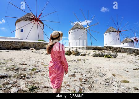 Young woman walking among traditional greek windmills on Mykonos island, Cyclades, Greece Stock Photo