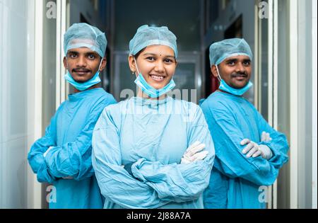 Team of young medical practitioners in operation gown confidently standing at hospital corridor - concept of career, professional occupation Stock Photo