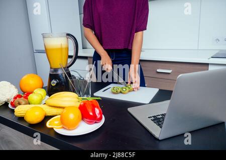 latino woman working at juice bar and cutting fruits, making fresh smoothies mixer blender from bananas,orange and melon. she useing eco metal Stock Photo