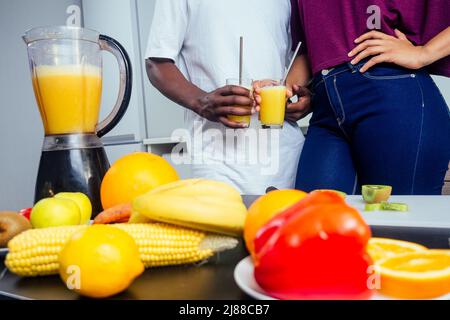 cropped shot of dark skinned couple making smoothies, pouring juice Stock Photo